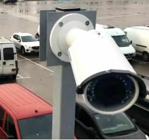 Уличная видеокамера на самодельном кронштейне направлена на стоянку авто