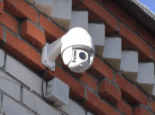 Поворотная видеокамера,  установленная на стене частного дома