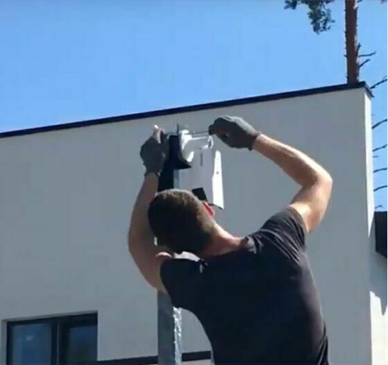 Монтажник устанавливает видеокамеру на самодельный столб