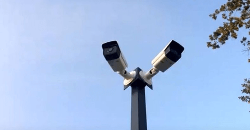 Две уличные видеокамеры , установленные на изготовленной стойке, направленные в разные стороны  опорах